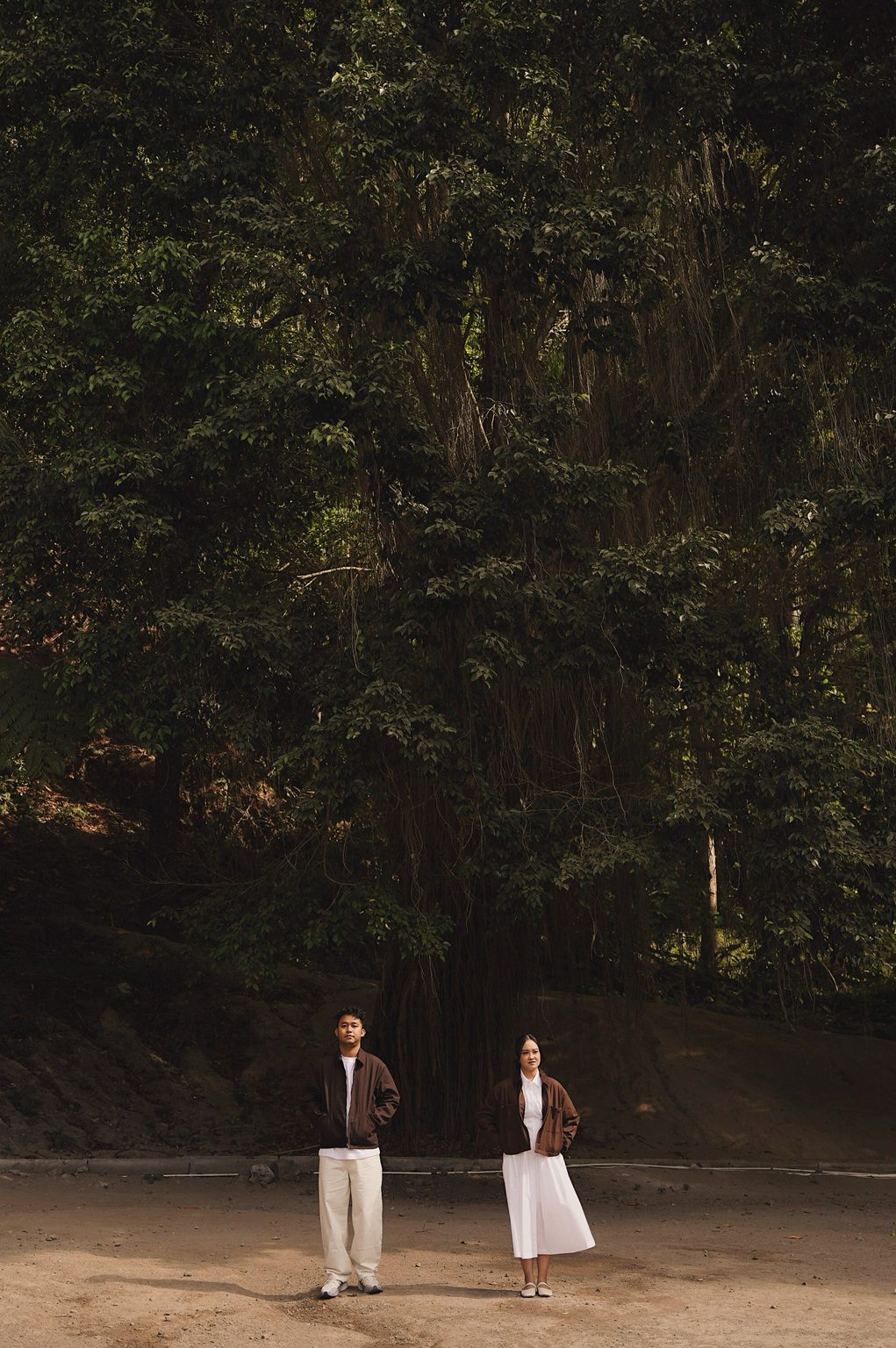 Brian and Sasa standing side by side beneath a towering tree