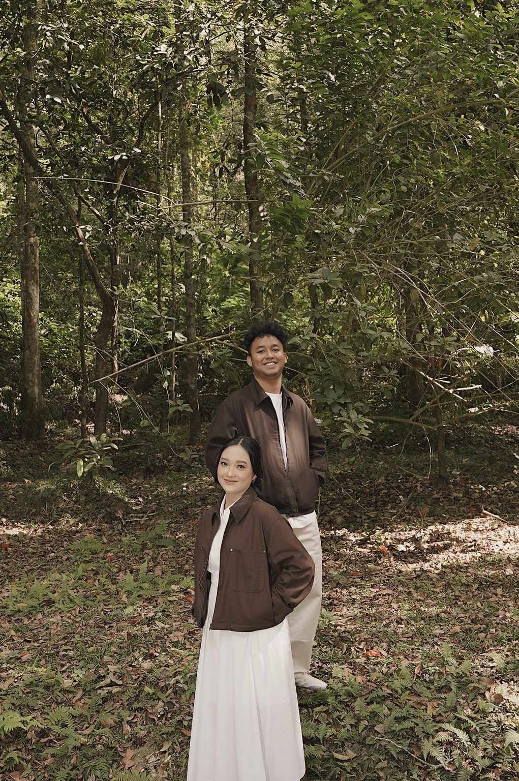 Sasa standing in front of Brian among the trees, both smiling