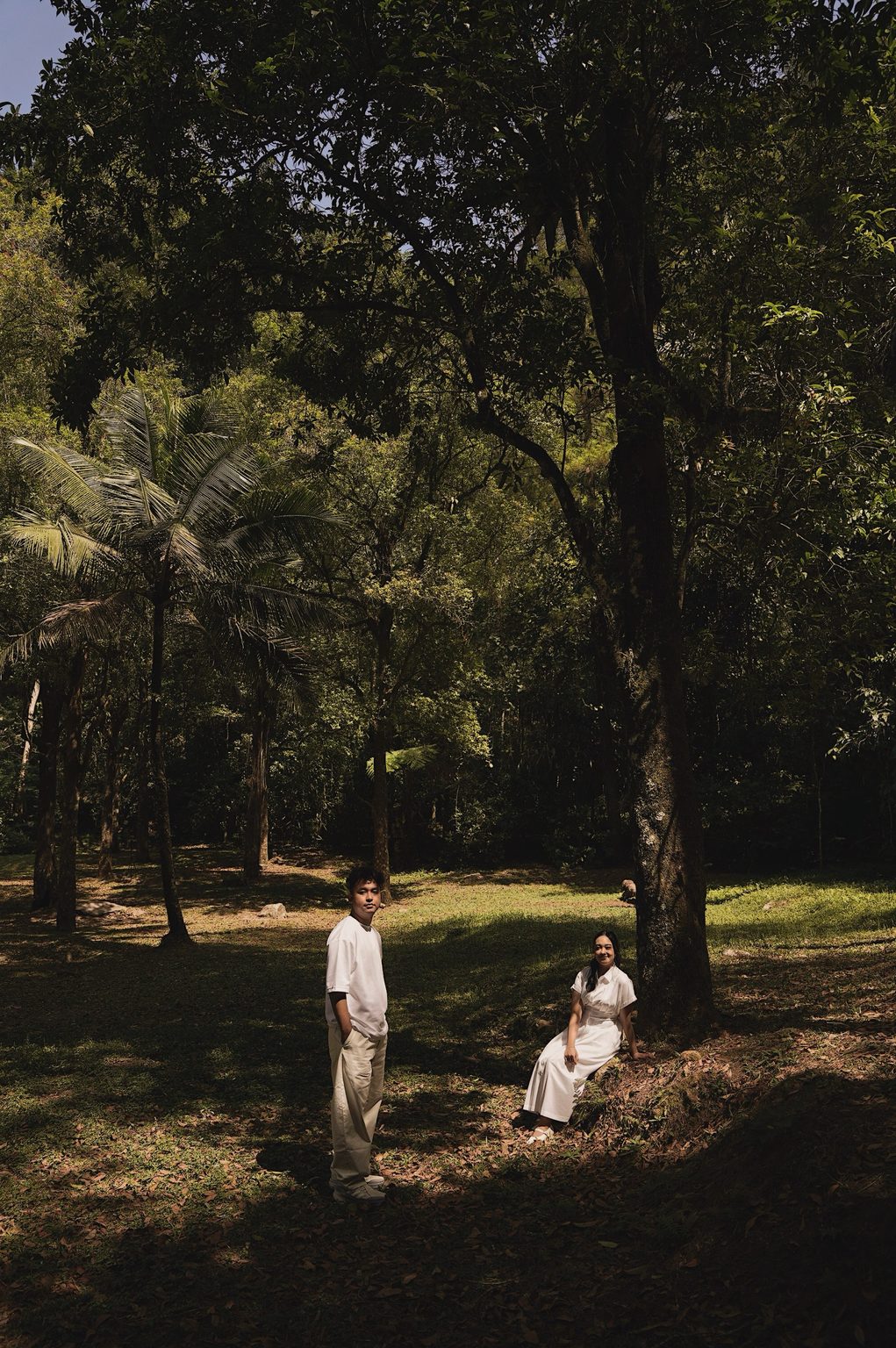 Brian standing and Sasa sitting beneath a large tree, both looking at the camera